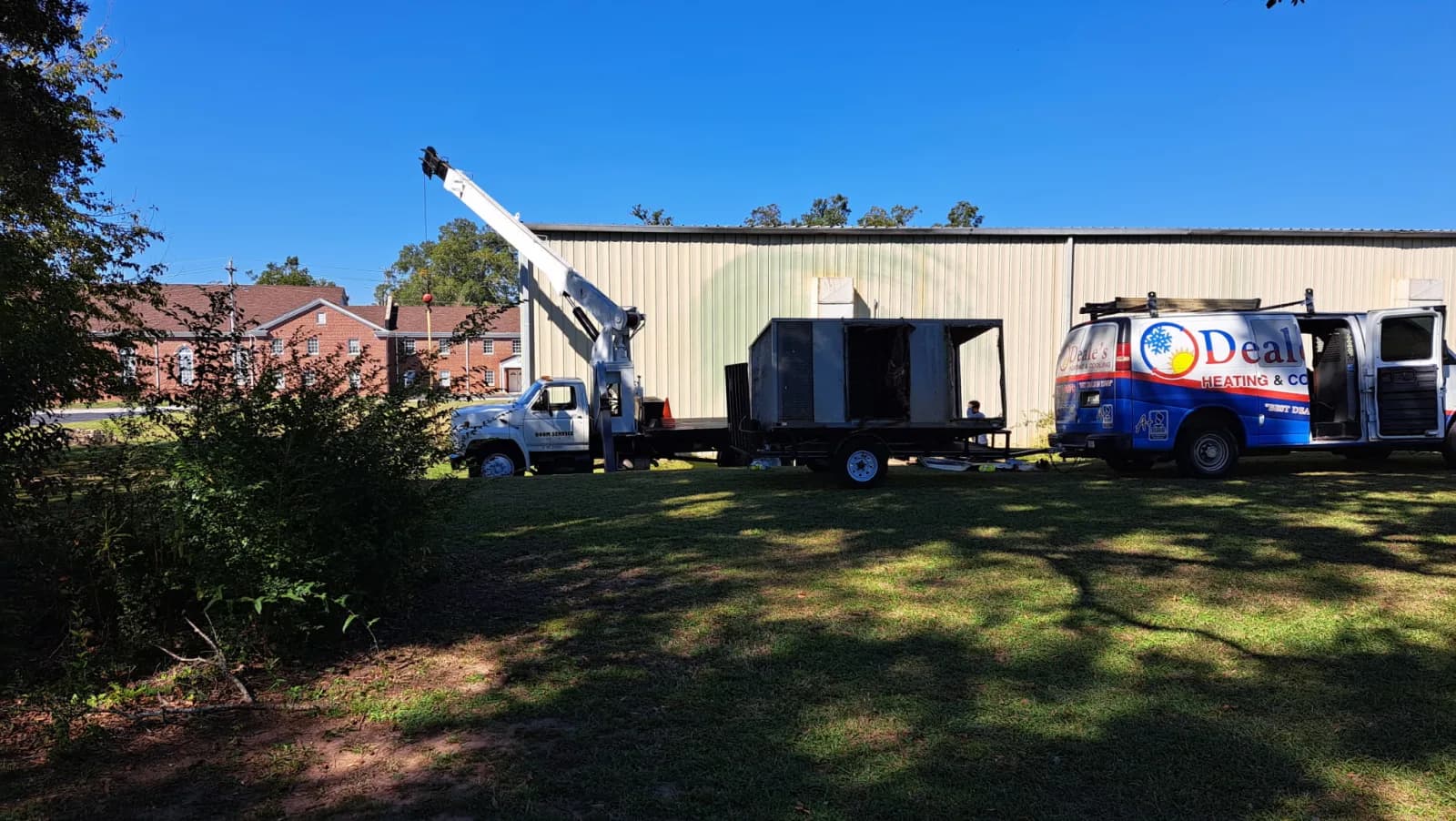 Boom truck placing a heavy air conditioning unit on a rooftop