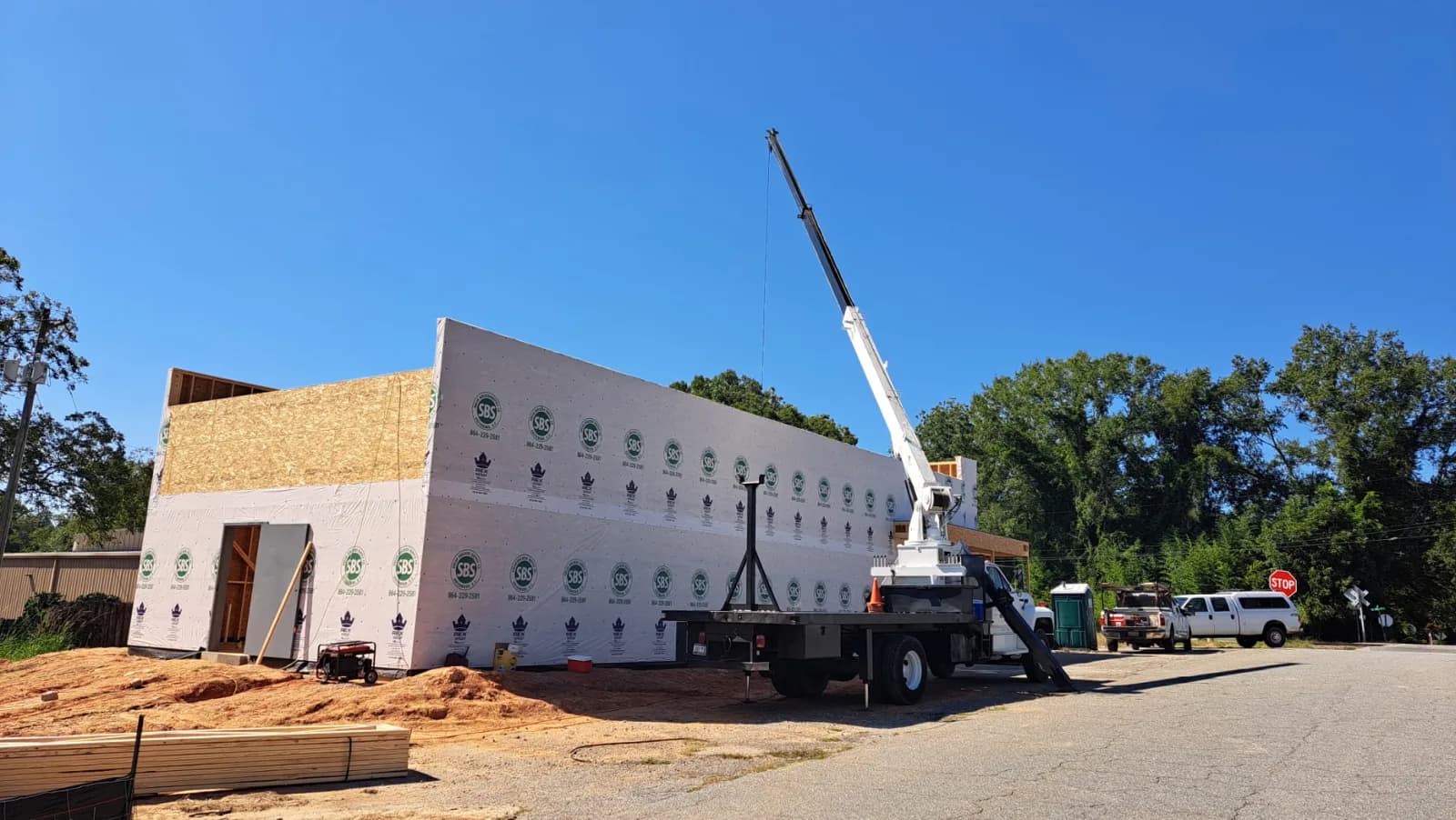 Boom truck lifting and setting a flat roof truss into place